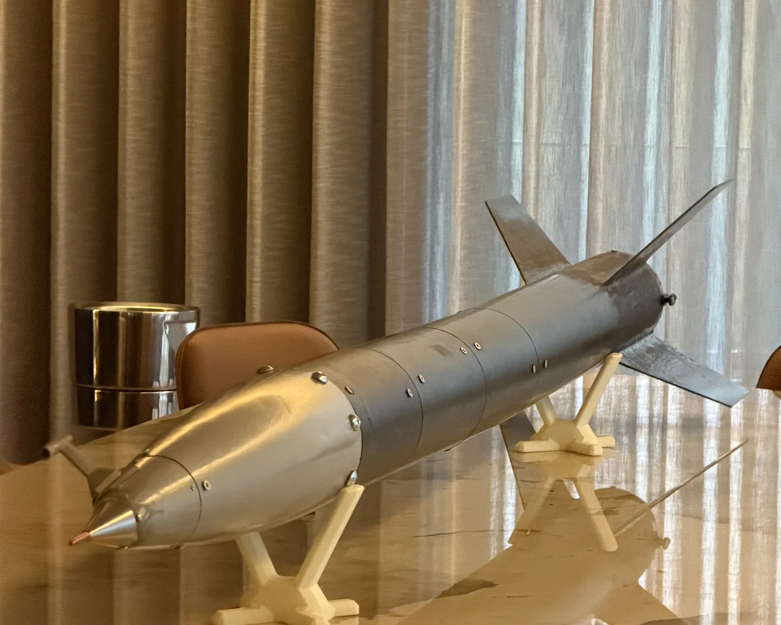 Lynxrocket V5 na horizontal sobre berços impressos: ogiva com ponta maquinada e sonda pitot-estática em primeiro plano, secções do corpo aparafusadas e o conjunto de aletas ao fundo